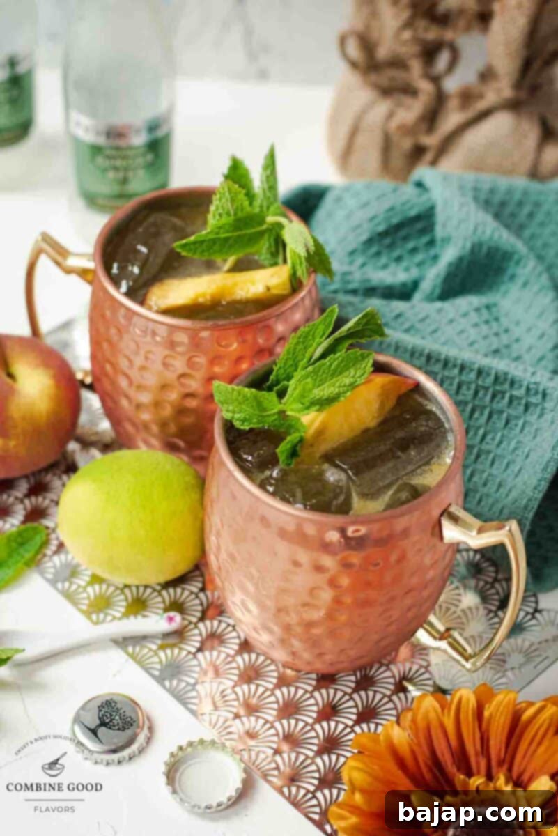 Delicious peach Moscow mule, served in copper mugs, garnished with peach slices and mint.