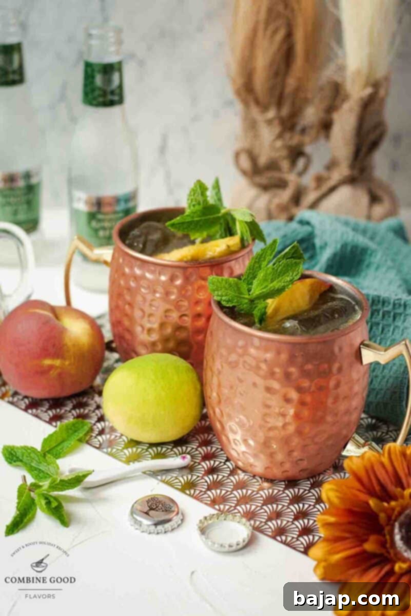 Delicious peach Moscow mule, served in copper mugs, garnished with peach slices and mint.
