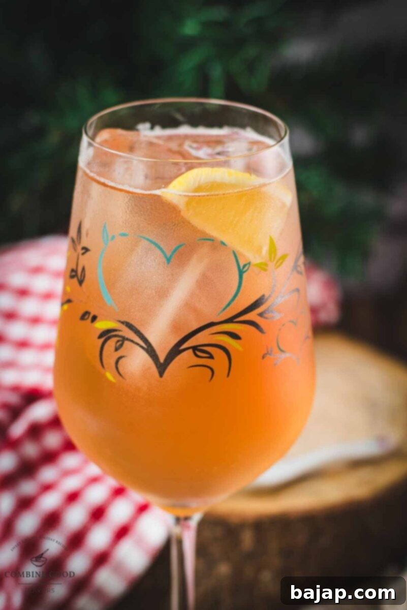 Delicious Zirben Spritzer served in a white wine glass. Placed on a wooden ground, evoking an alpine setting.