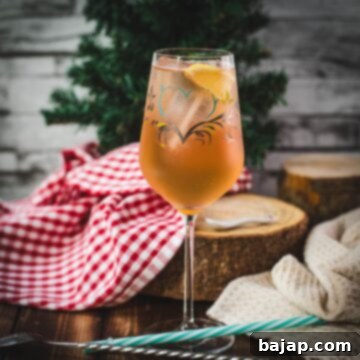 Delicious Zirben Spritzer served in white wine glass. Placed on wooden ground, next to a flask of Zirben Schnapps.