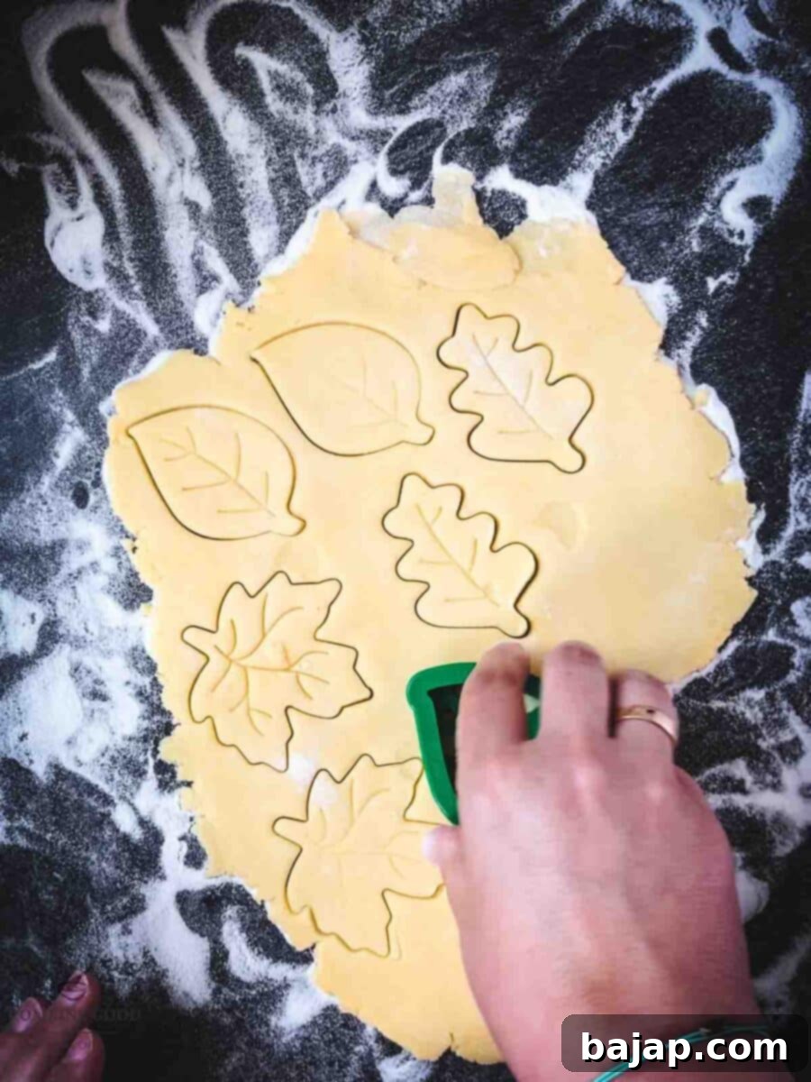 Raspberry Swirl Autumn Leaf Cookies 9 Rolling out and cutting the shortbread cookie dough into leaf shapes with cookie cutters.