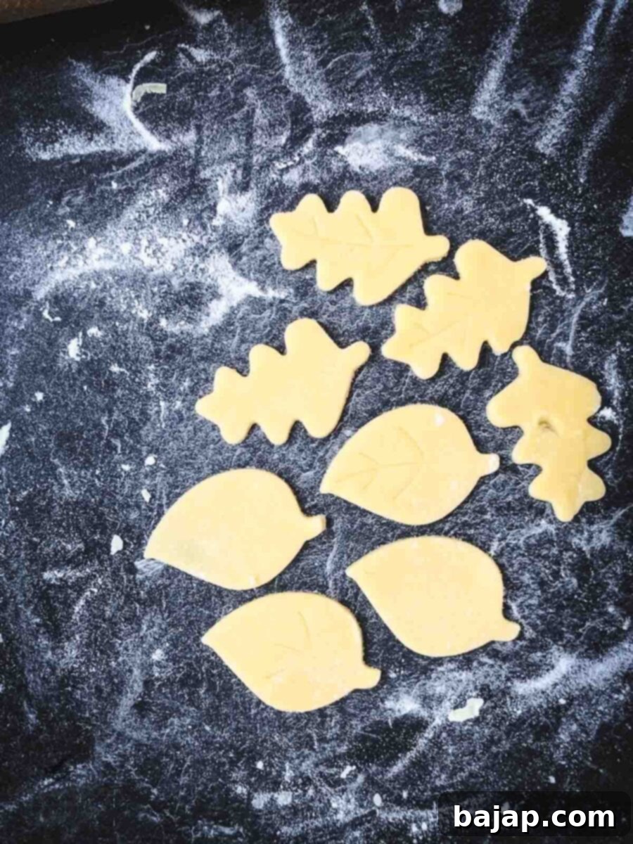 Raspberry Swirl Autumn Leaf Cookies 10 Several raw leaf-shaped cookie dough cutouts arranged on a baking sheet, ready for the oven.