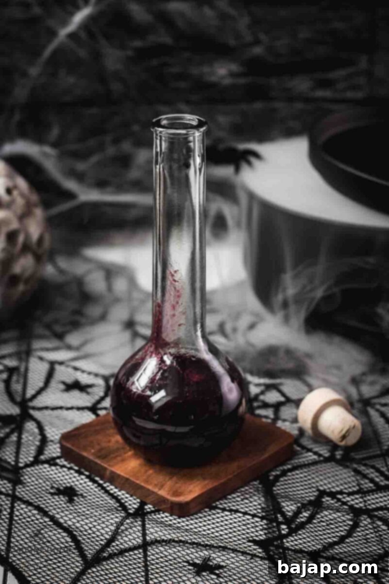 Eerily beautiful, decorated with cobwebs and a black, steaming cauldron, setting a spooky scene for Halloween berry blood syrup.