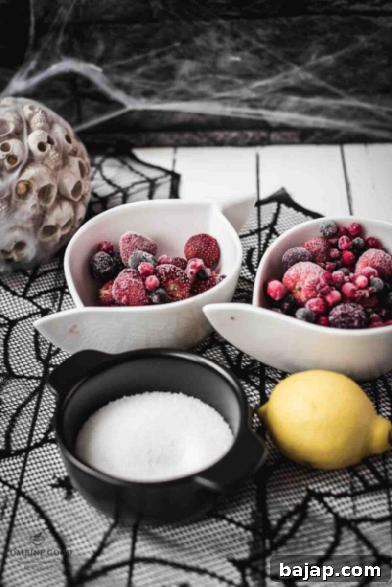 Easy 3-Ingredient Fake Blood 3 Ingredients for berry blood syrup - a bowl of frozen berry mix, a bowl of sugar, and a lemon.