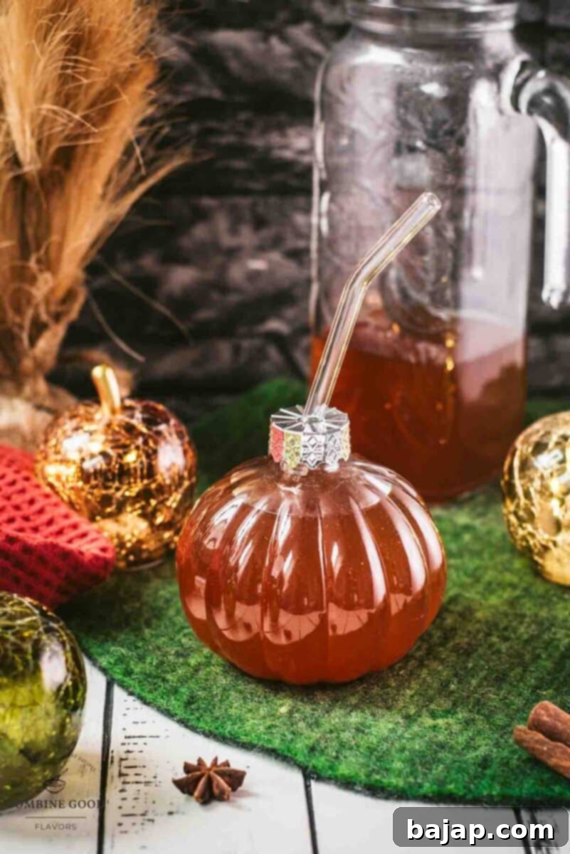 Homemade spiced apple cider in pumpkin shaped drinking glass.