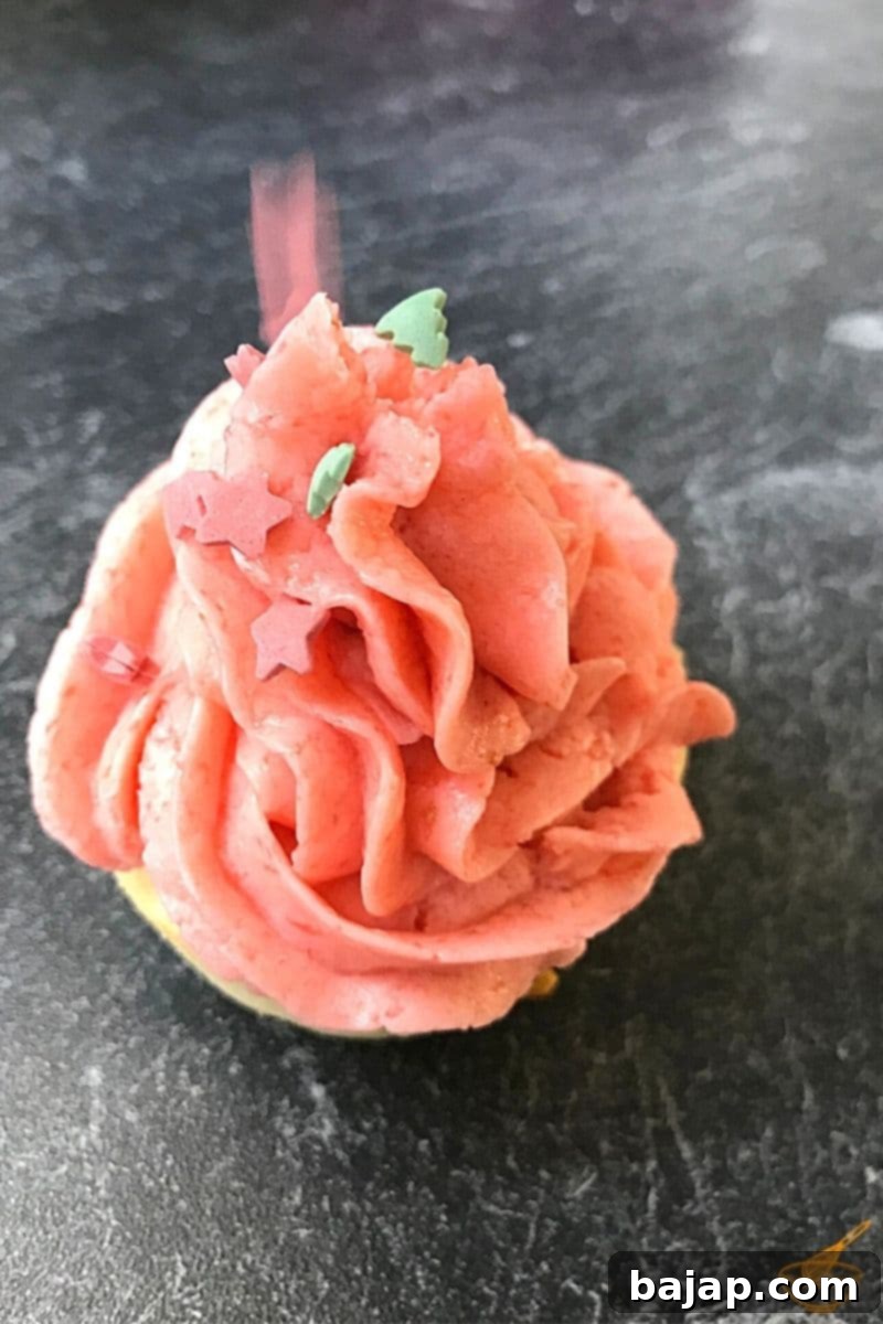 Luscious Strawberry Ricotta Cupcakes 11 Close-up of a fresh Strawberry Ricotta Cupcake with pink buttercream, light and fluffy texture, subtle ricotta sponge, and dominant strawberry taste.