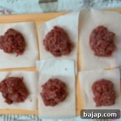 Portions of minced meat on sandwich paper, ready for shaping.