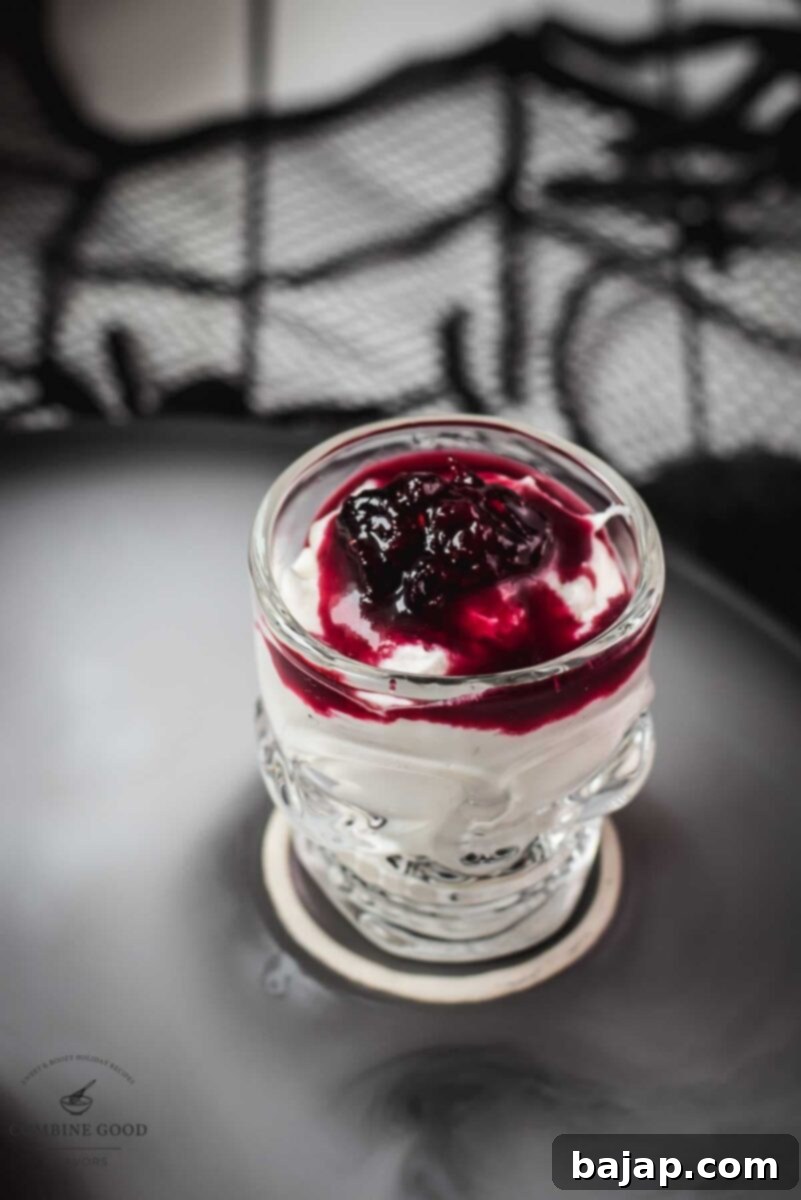 Spooky blood clot berry brains mousse, served in skull shaped shot glasses. Multiple skull-shaped glasses filled with the 