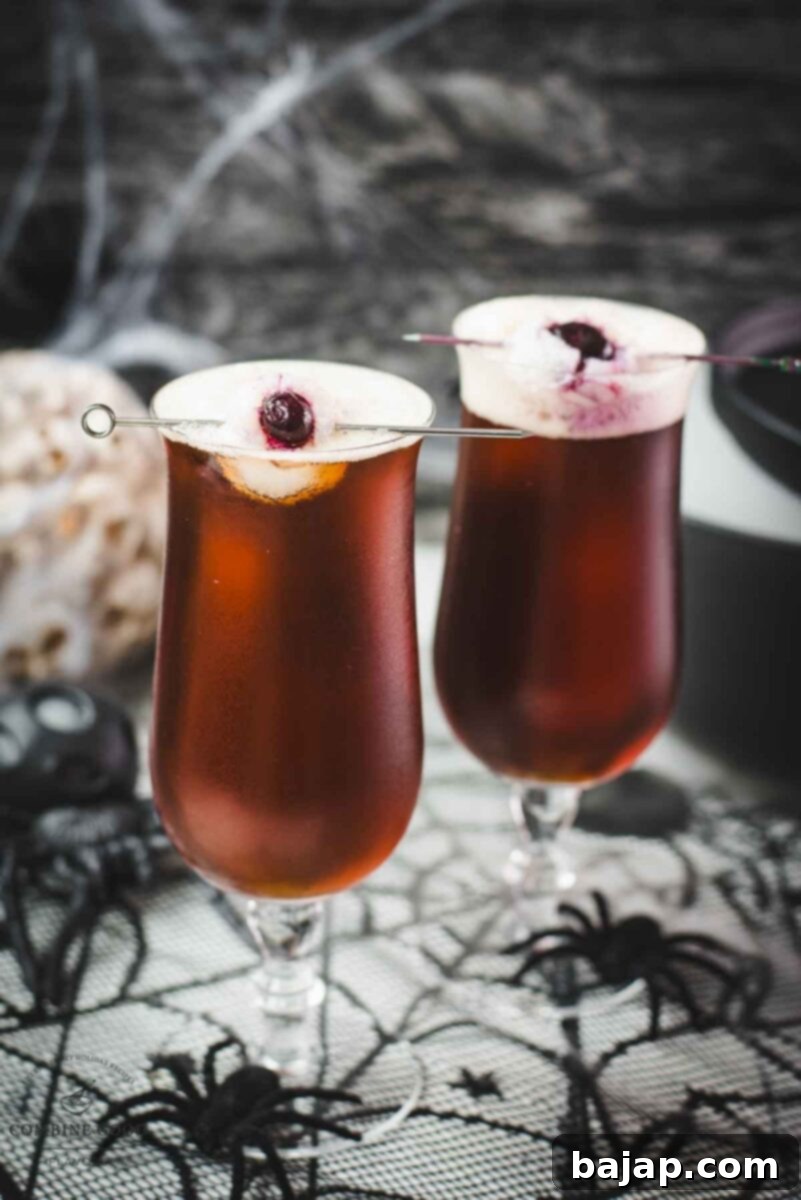 Spooky black velvet cocktail, garnished with eerie lychee eyeballs. A dark, bubbling drink perfect for a Halloween party.