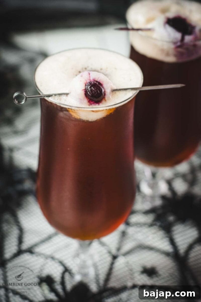 A black velvet cocktail with lychee eyeball garnish, casting a spooky shadow. Perfect for a Halloween drink.