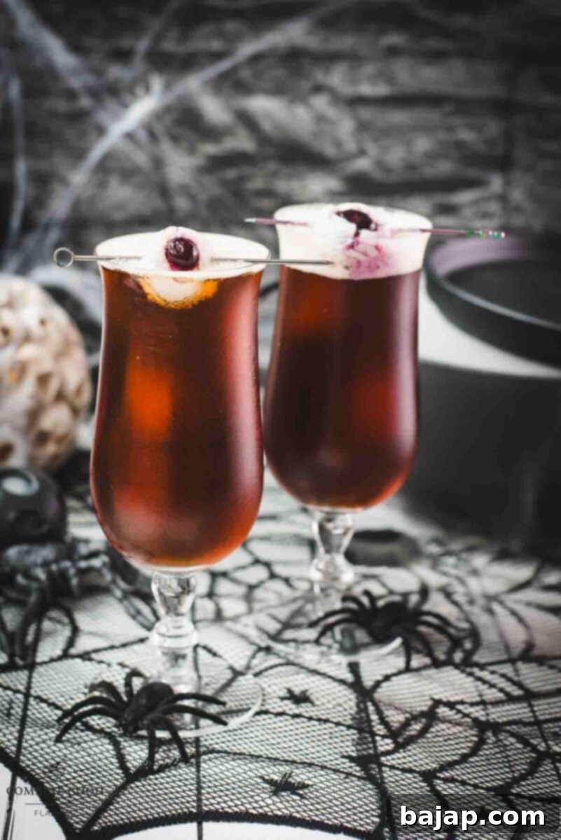 Close up of a Black Velvet Halloween cocktail with its eerie lychee eyeball, ready to be served.