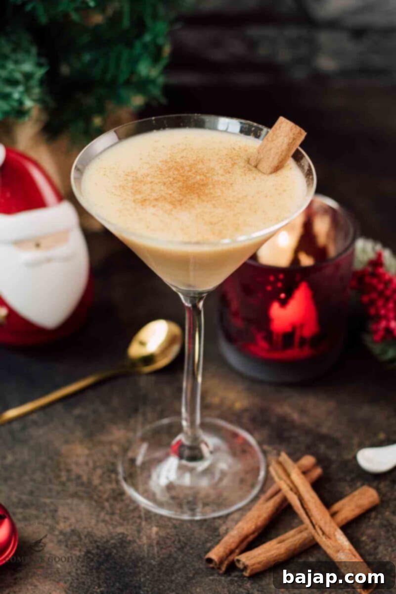 Holiday Nog Dream 2 Delicious eggnog martini dusted with ground cinnamon and garnished with a cinnamon stick, ready for a festive holiday celebration.