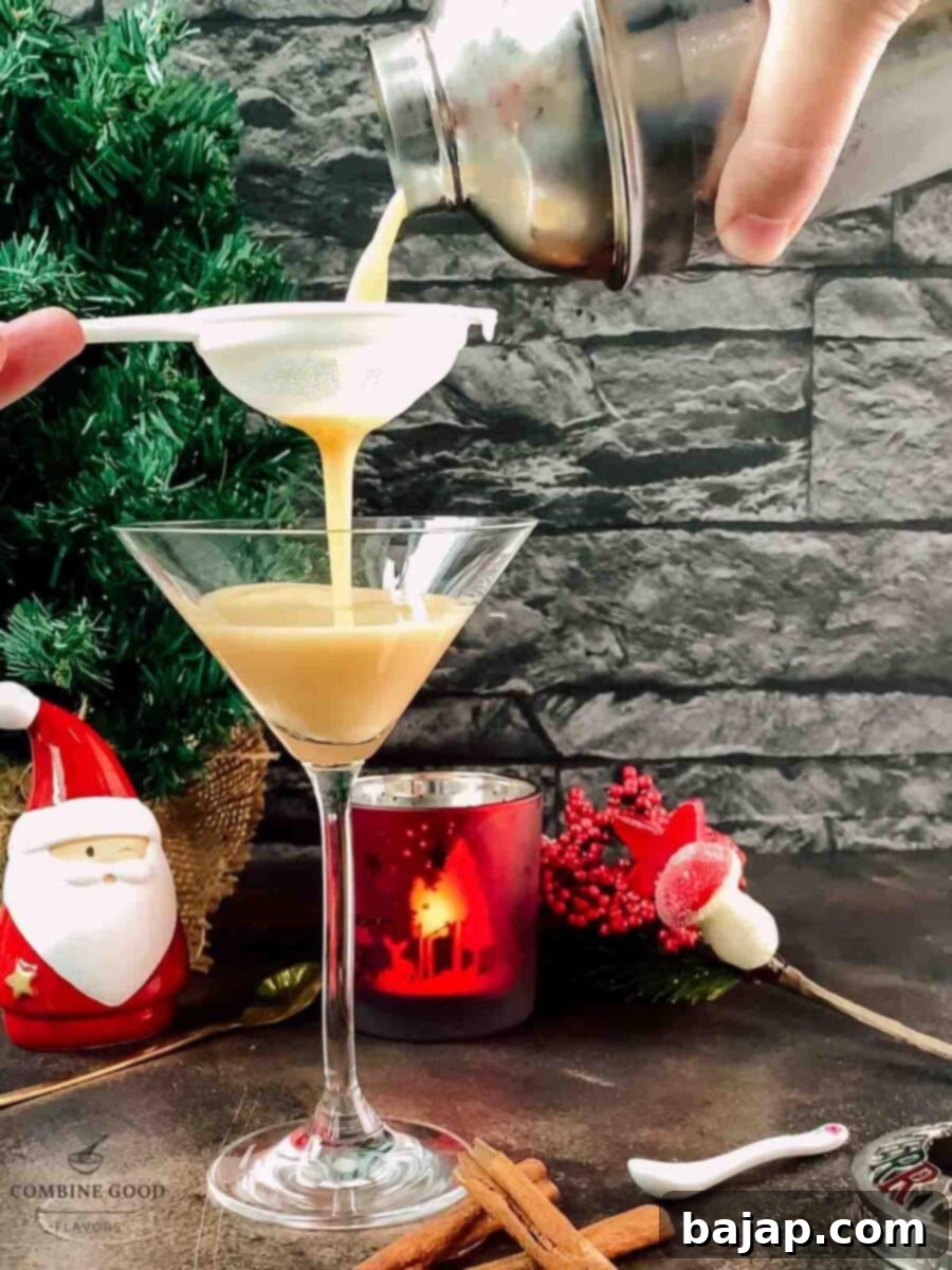 Holiday Nog Dream 7 Fine straining the eggnog martini mixture into a chilled serving glass for a smooth finish.