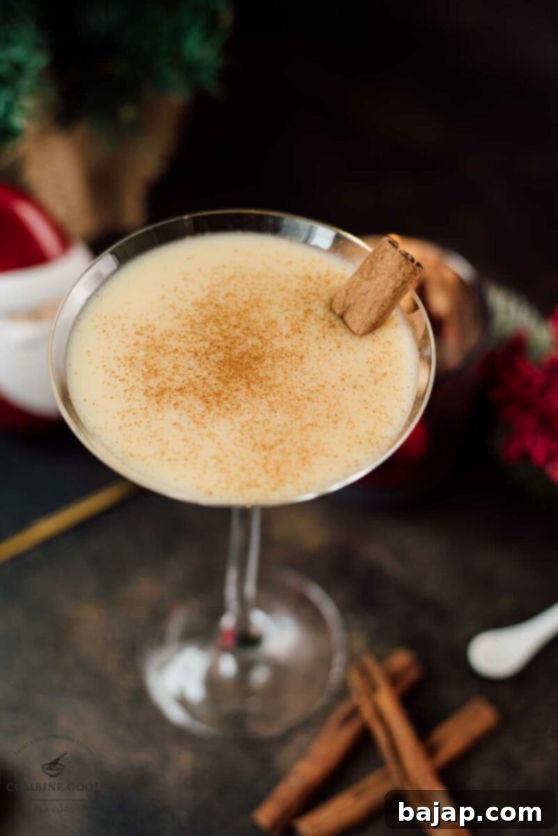 Holiday Nog Dream 8 Delicious eggnog martini dusted with ground cinnamon and garnished with a cinnamon stick, ready for a cozy holiday evening.
