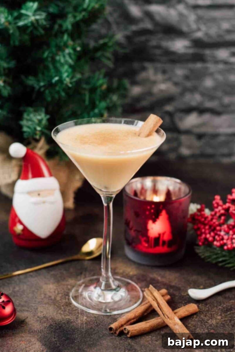 Holiday Nog Dream 10 Delicious eggnog martini dusted with ground cinnamon and garnished with a cinnamon stick, capturing the holiday spirit.