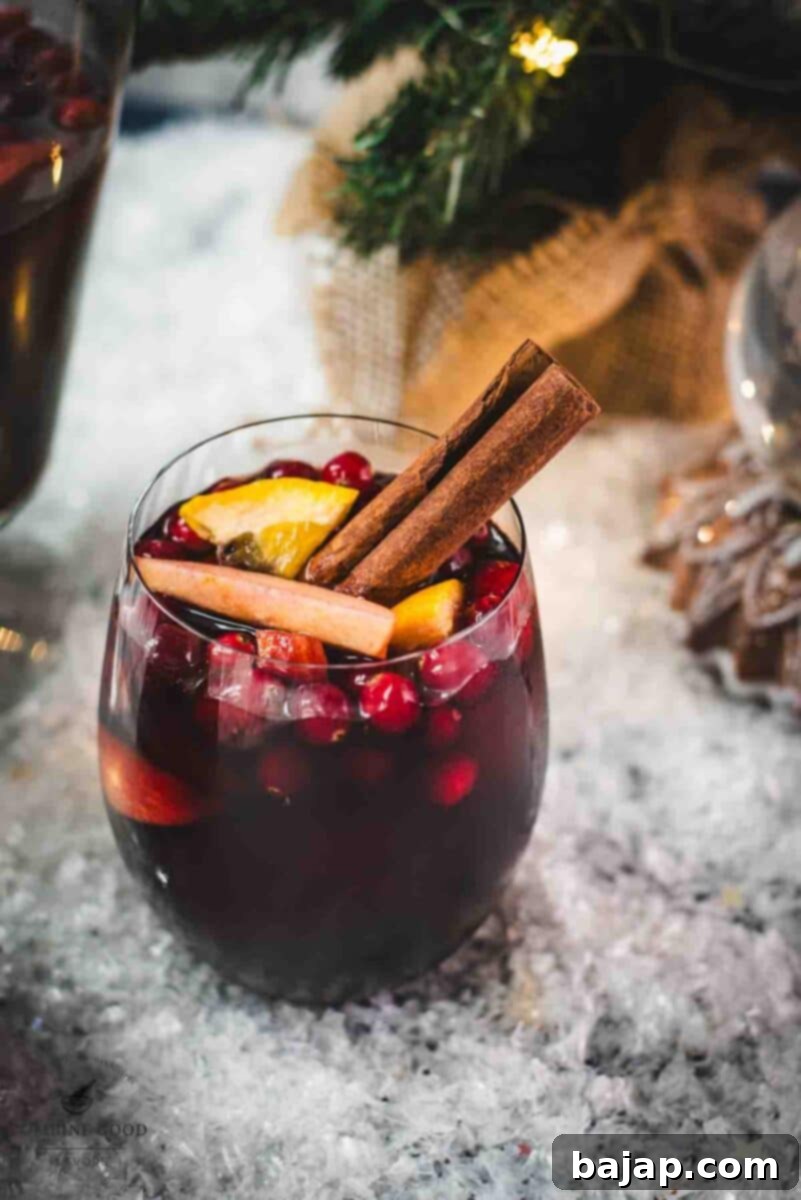 A festive glass of non-alcoholic spiced winter sangria, garnished with cinnamon stick and star anise, perfect for holiday gatherings.