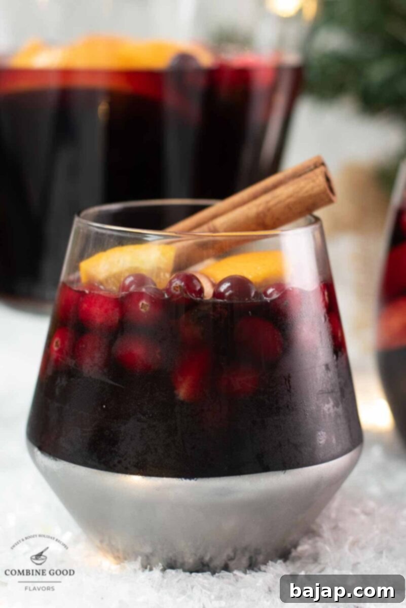 Another beautiful glass filled with non-alcoholic spiced winter sangria, garnished with a cinnamon stick, ready for holiday enjoyment.
