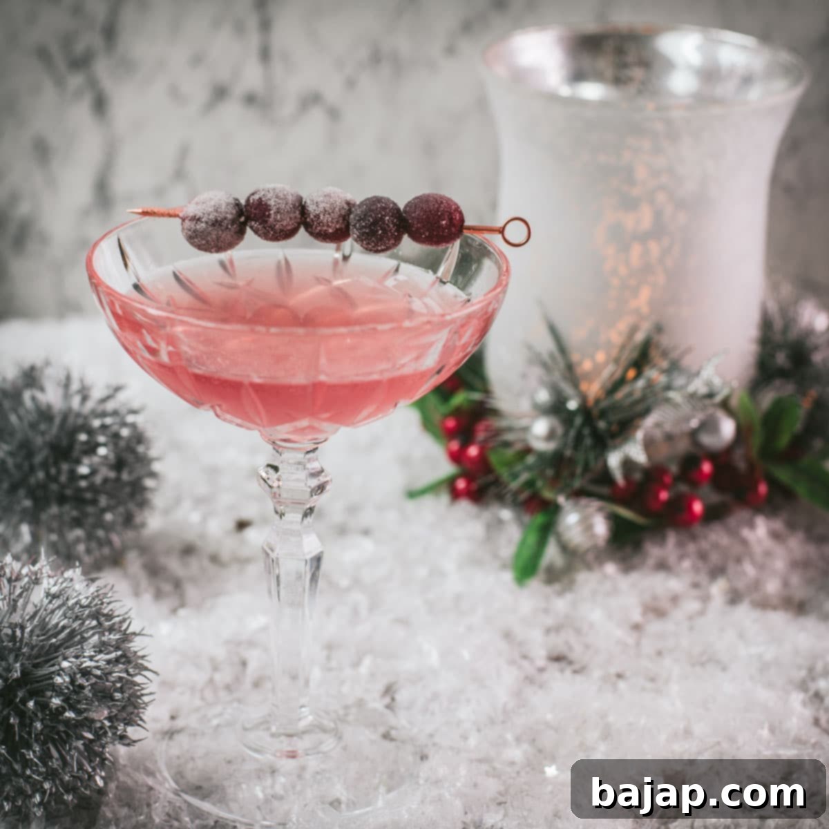 Gorgeous pink cranberry maraschino sour garnished with iced cranberries on a cocktail skewer.