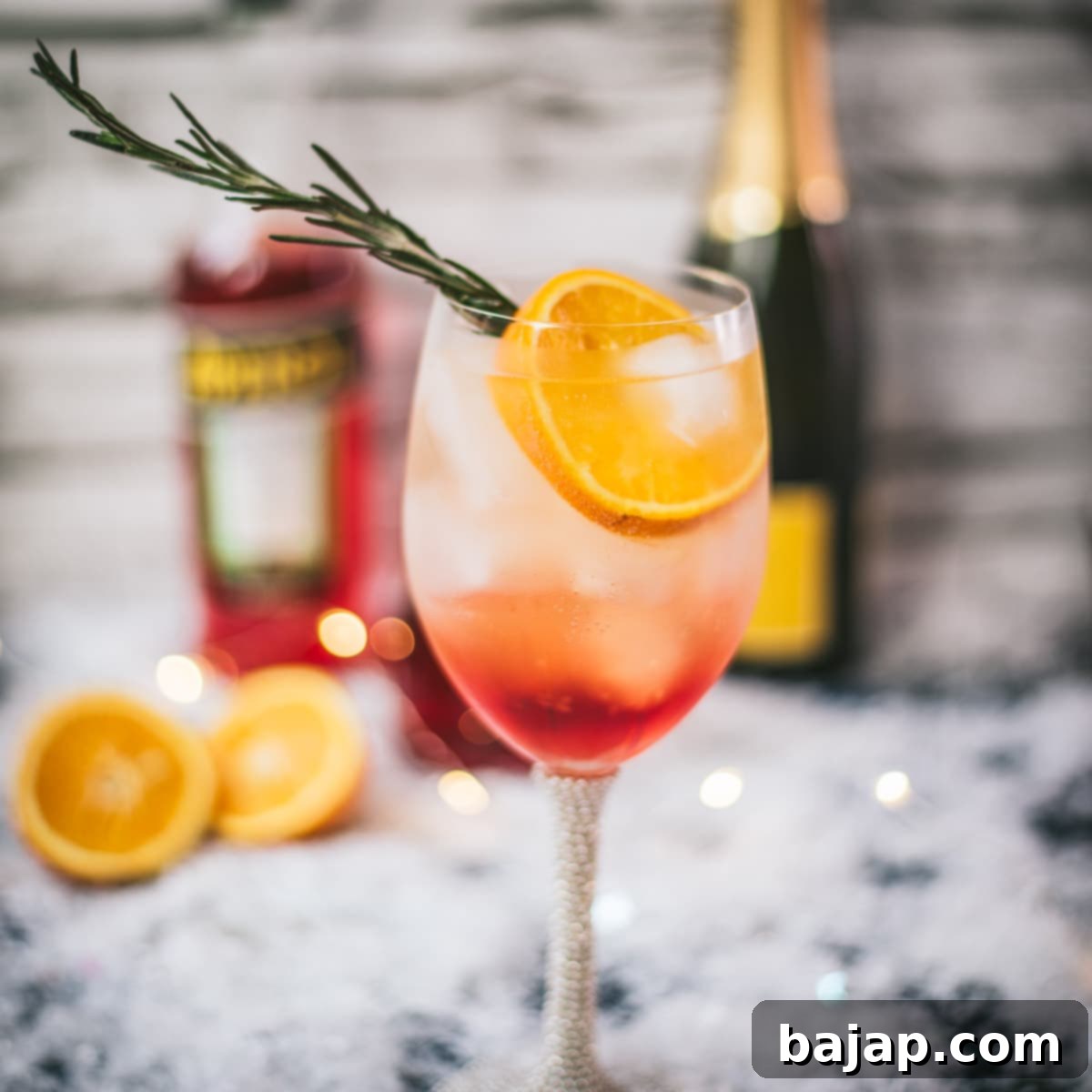 Gorgeous wine glass filled with Winter Aperol spritz, placed on snowy ground.