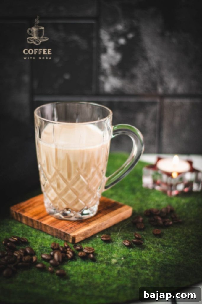 Glass mug filled with coffee and milk on a wooden coaster, showcasing a typical coffee drink.
