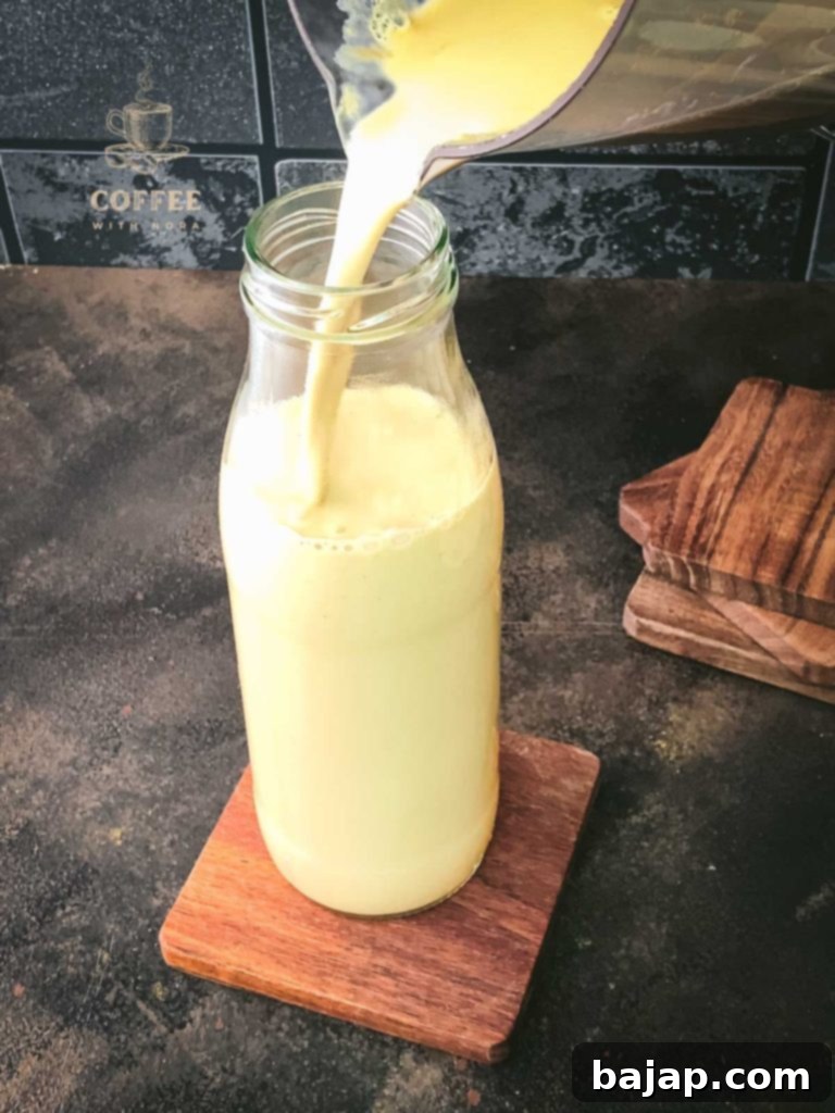 Festive Holiday Coffee Creamer 8 Pouring the cooled Christmas coffee creamer into a preserving jar.