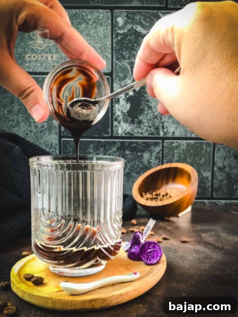 Adding chocolate syrup to an espresso shot.