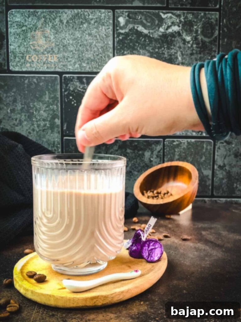 Stirring together coffee, chocolate syrup, and steamed milk.