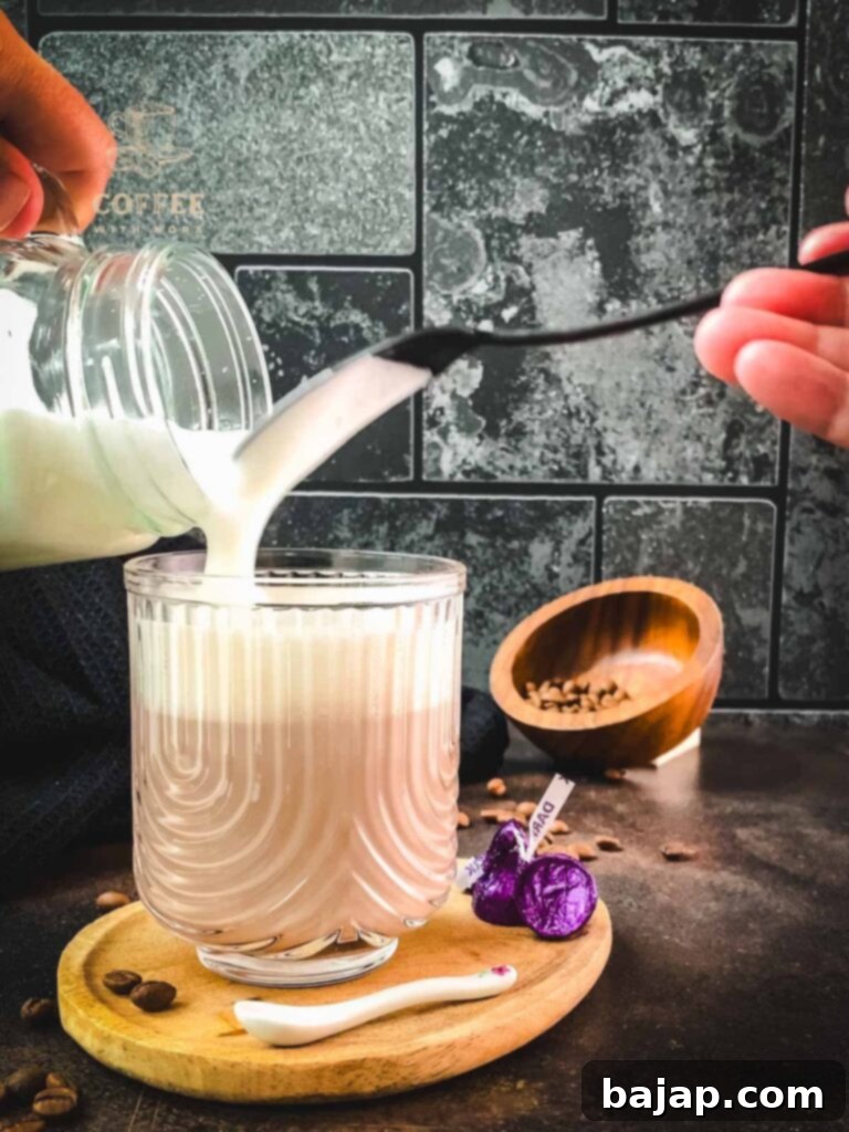 Topping the mocha with frothed milk.