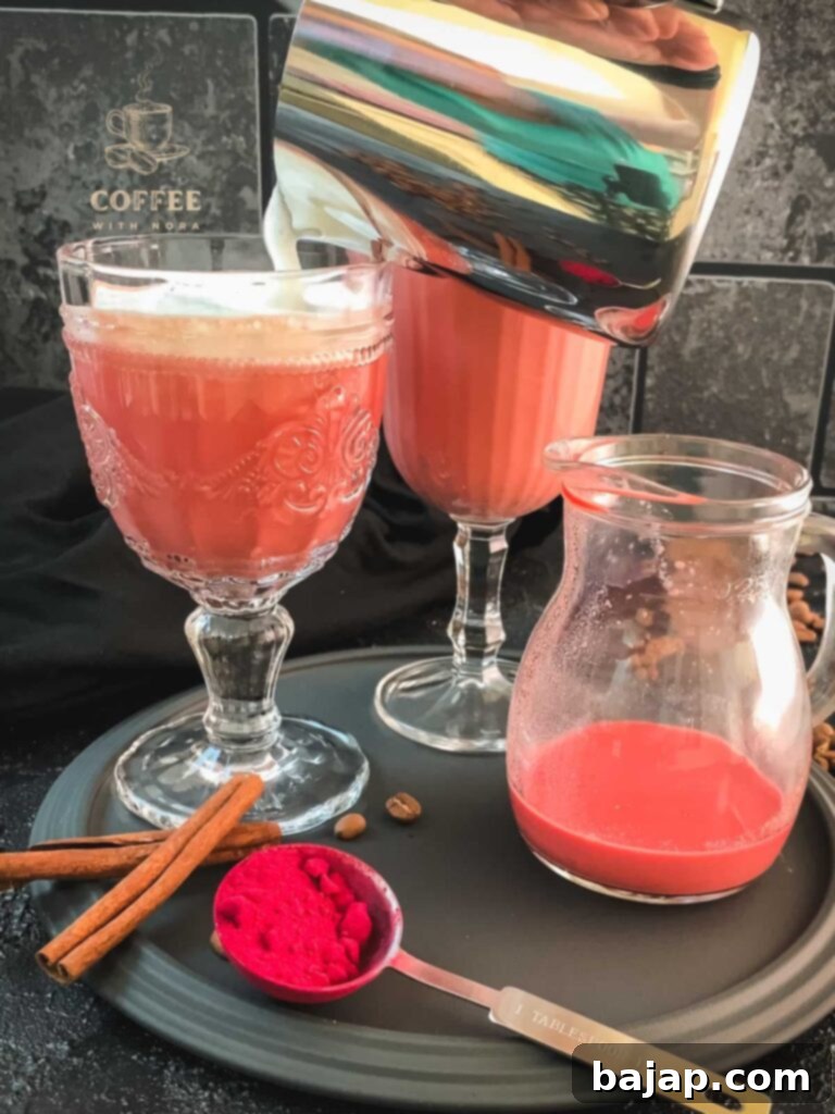 Adding a layer of frothed milk to the pink latte.