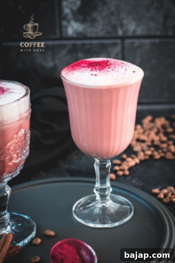 A delicious pink latte in a beautiful glass on a dark plate.