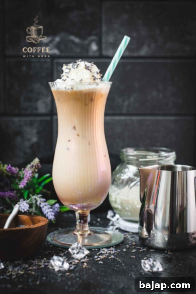 Lavender Dream Iced Latte 9 Iced Lavender Latte in Hurricane Glass with Whipped Cream and Lavender Buds with a straw.