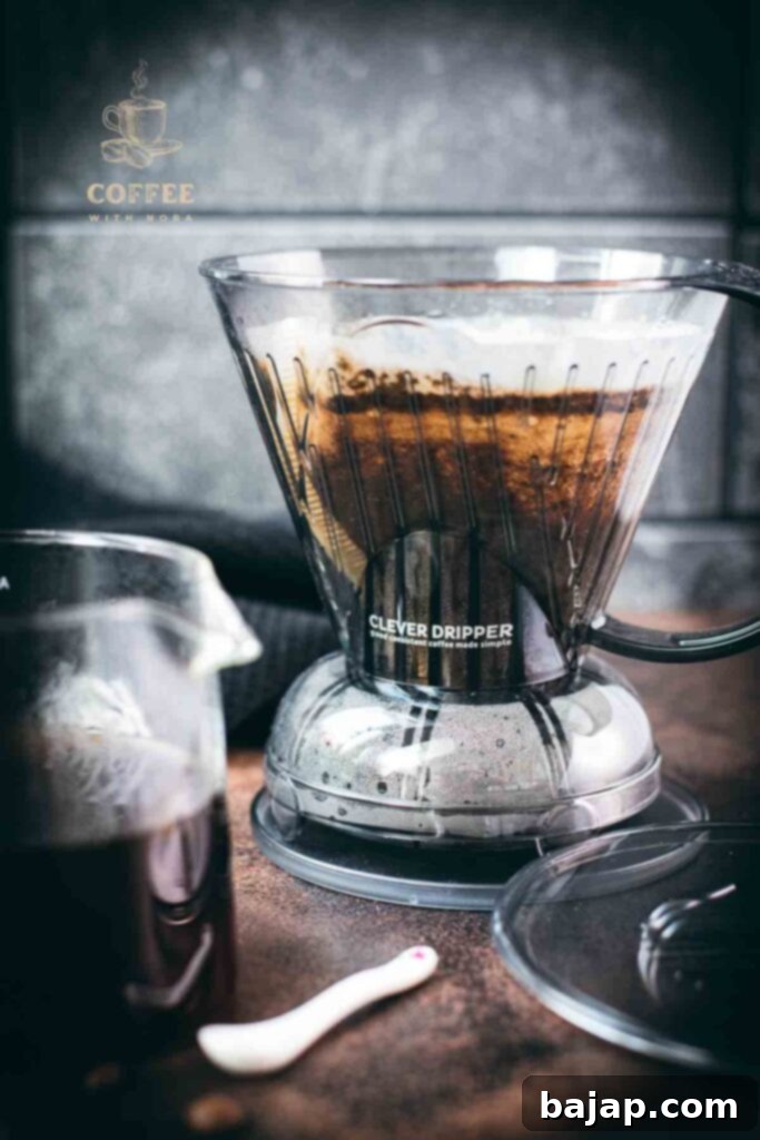 Hoffmann Method Reverse Clever Dripper Brew 1 Reverse Clever Dripper placed on a dark surface, with a glass carafe filled with coffee beside it.