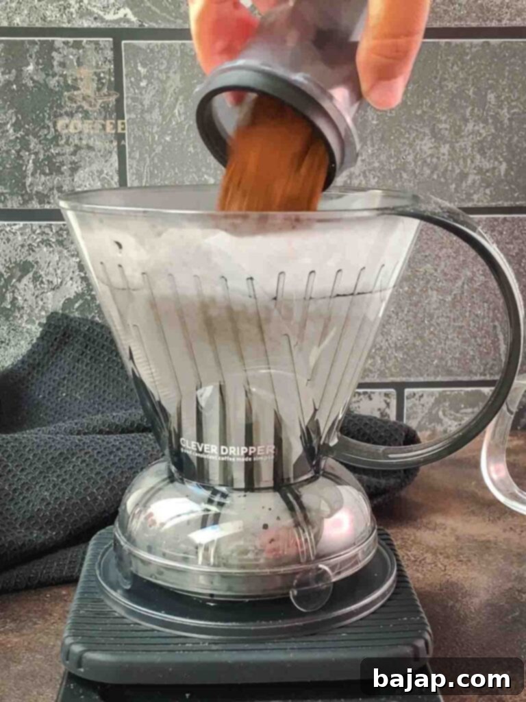 Hoffmann Method Reverse Clever Dripper Brew 3 Pouring medium-coarse ground coffee into the heated water.