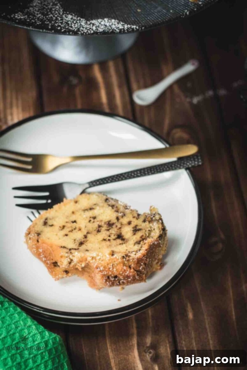Vanilla Bean Bundt Cake with Dark Chocolate Drizzle 3 A slice of delicious vanilla bundt cake with chocolate sprinkles, served on a black and white plate.
